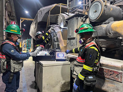 Workers check the emissions after a Diesel Particulate Filter was installed on equipment at PTFI. They are Esron Pinto, left, Superintendent, Mobile Fire System and Emissions Maintenance; Nelson Sugianto Simanjuntak, Foreman, Mobile Maintenance; and Pilemon Ronald Deda, Superintendent, Mobile Maintenance